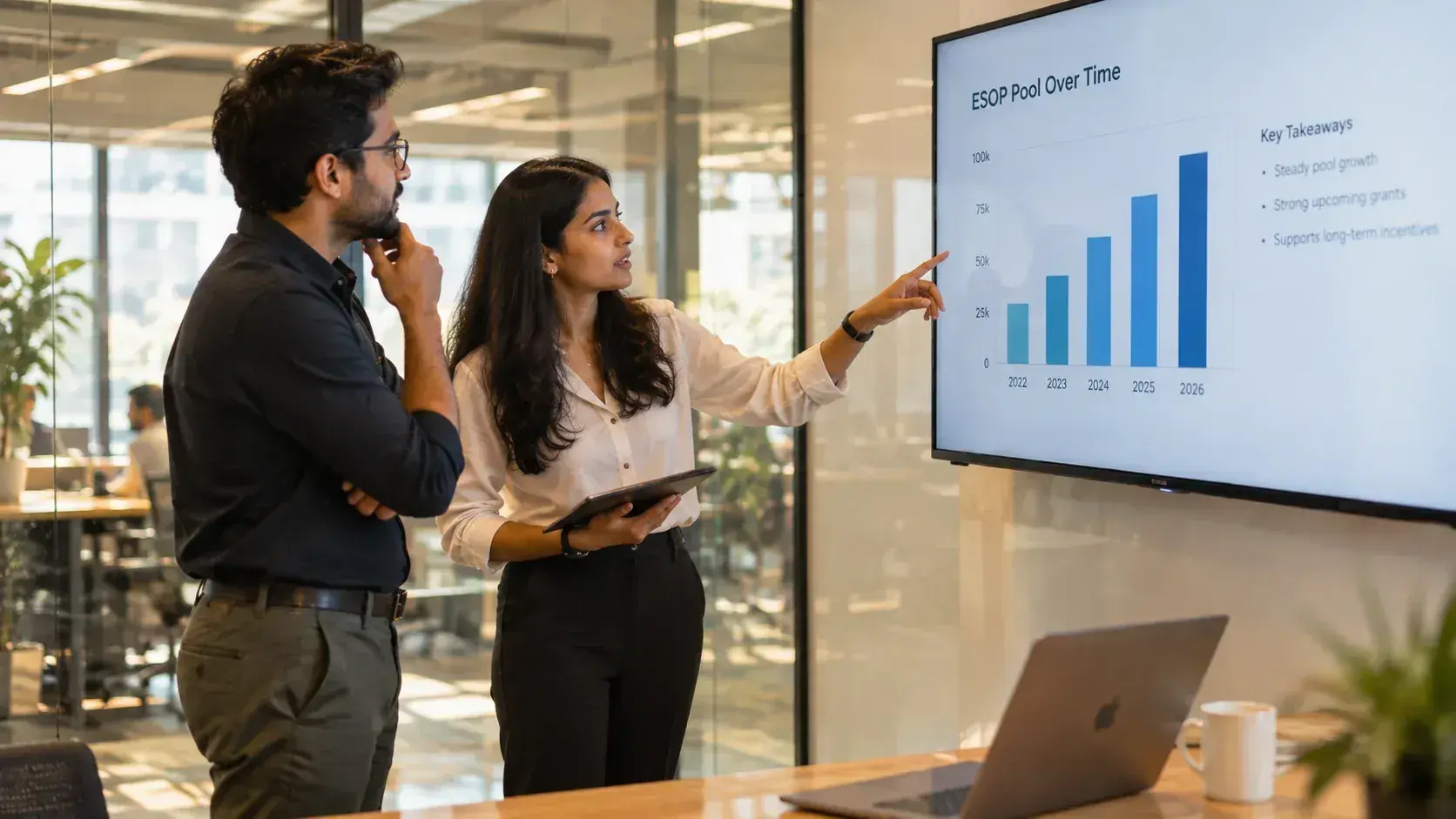 Two colleagues reviewing a chart of ESOP pool growth on a meeting room screen
