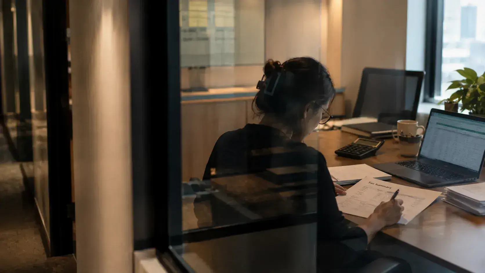A finance professional working through a tax summary beside a spreadsheet late in the day