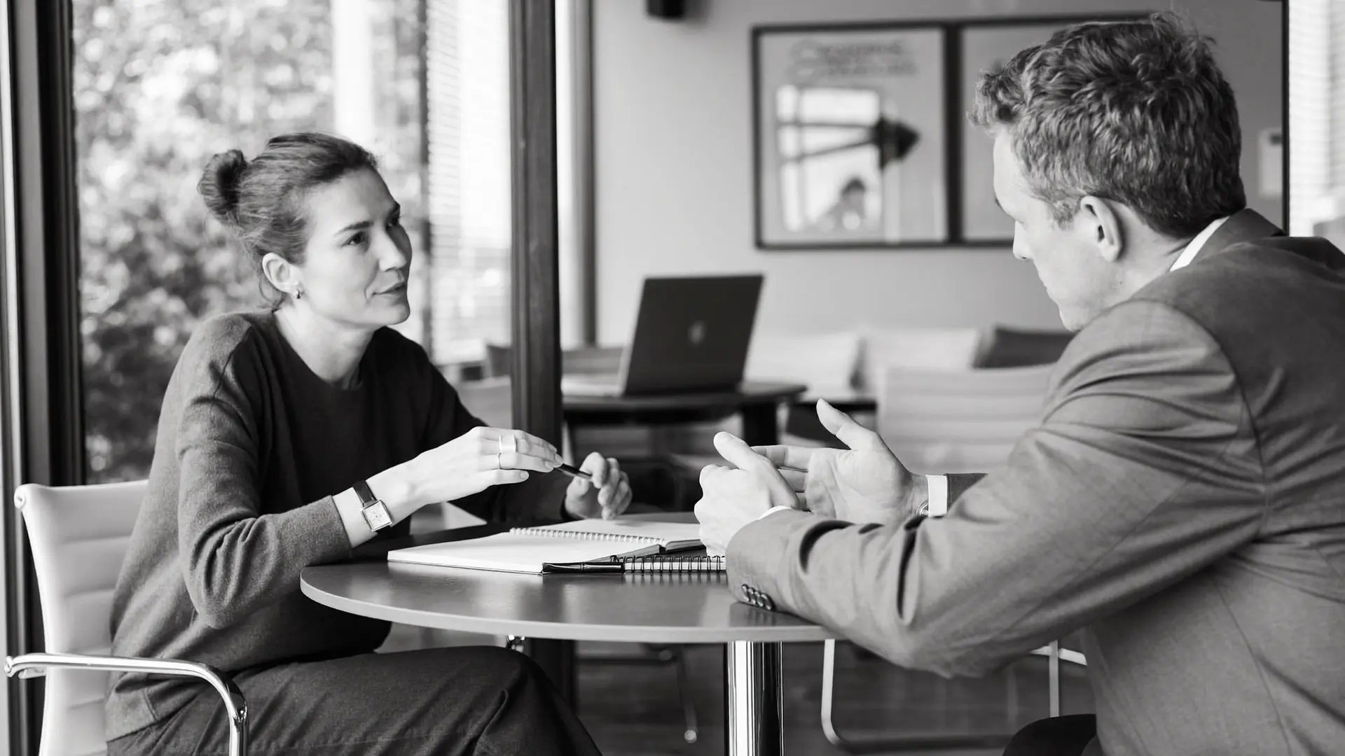 A manager and a colleague in a focused one to one conversation in a glass meeting room