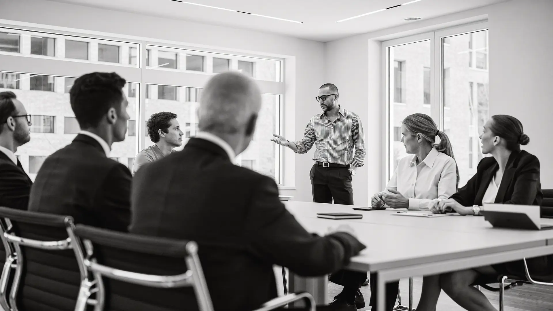 A senior executive addressing colleagues in a modern boardroom