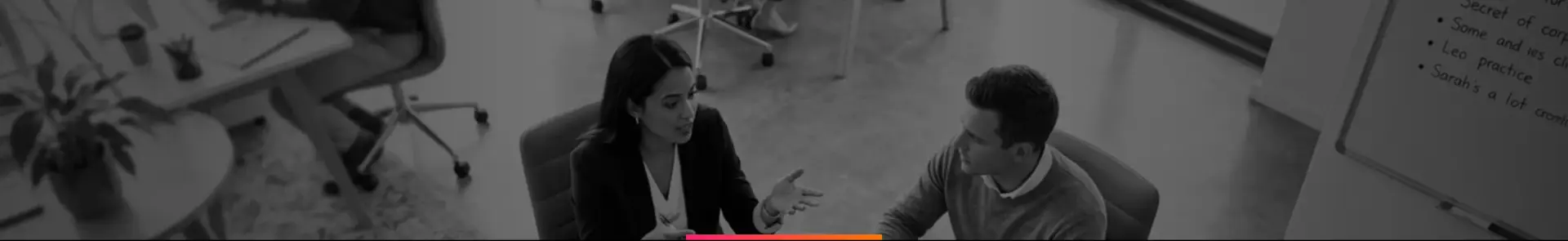 Black-and-white photo of two colleagues in a meeting at an office table