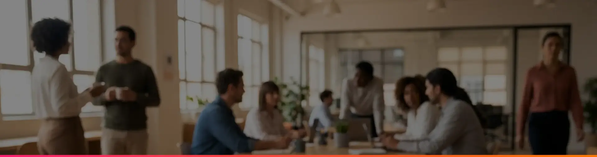 A laptop showing a fair compensation analysis dashboard on a wooden table, with colleagues talking in the background.