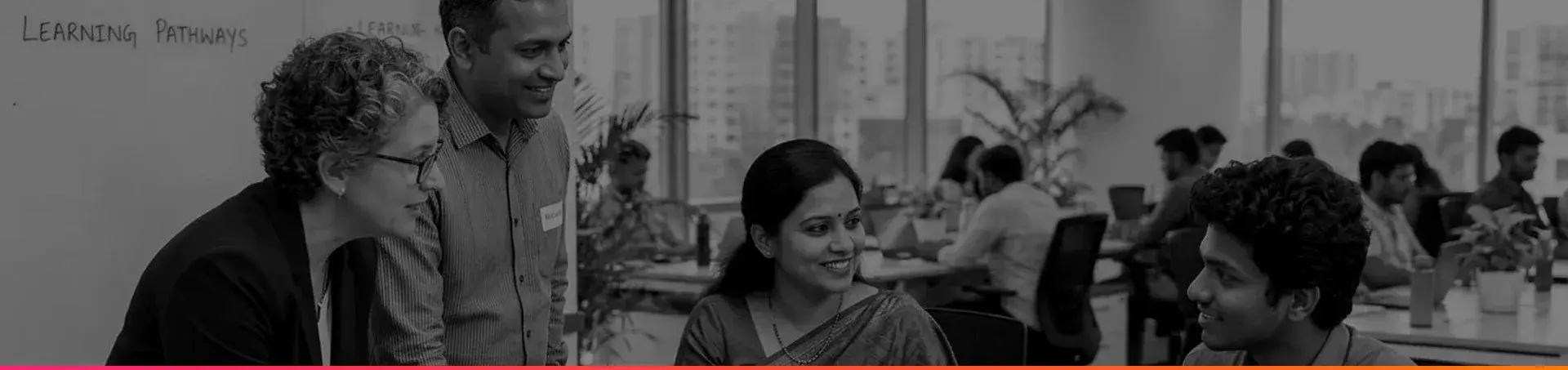 HR leader talking with three colleagues around a table in an open-plan office.