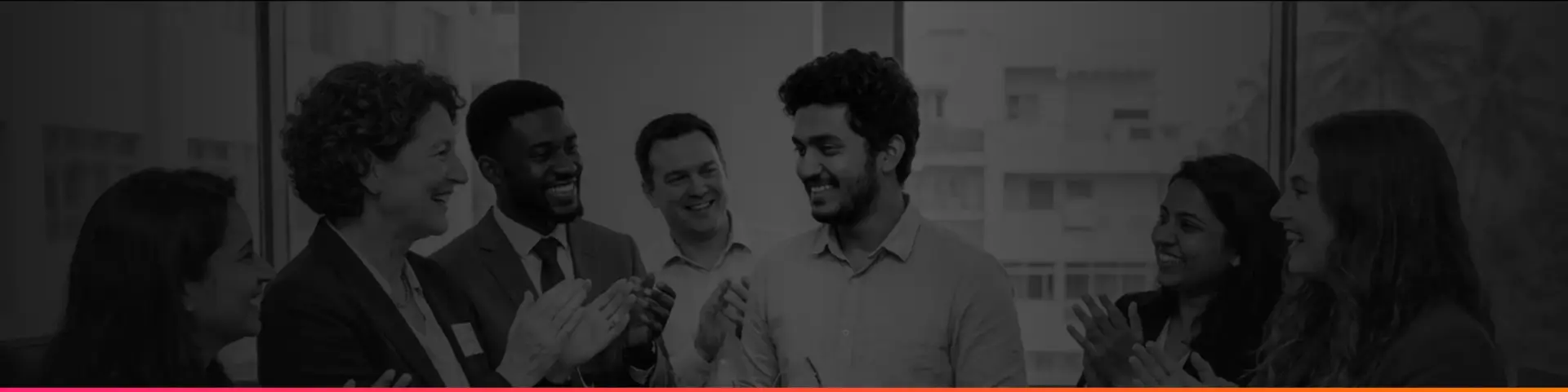 Black-and-white photo of a group of colleagues smiling and applauding in an office