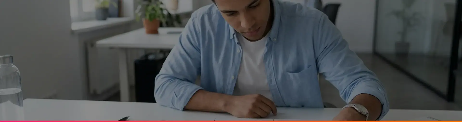 A man fitting together jigsaw pieces on a white desk in a bright office