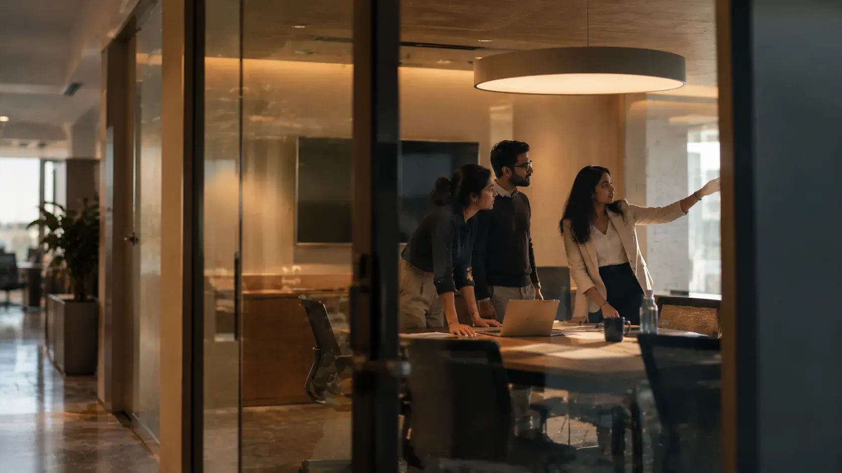Three colleagues reviewing a financial model on a screen in a meeting room.